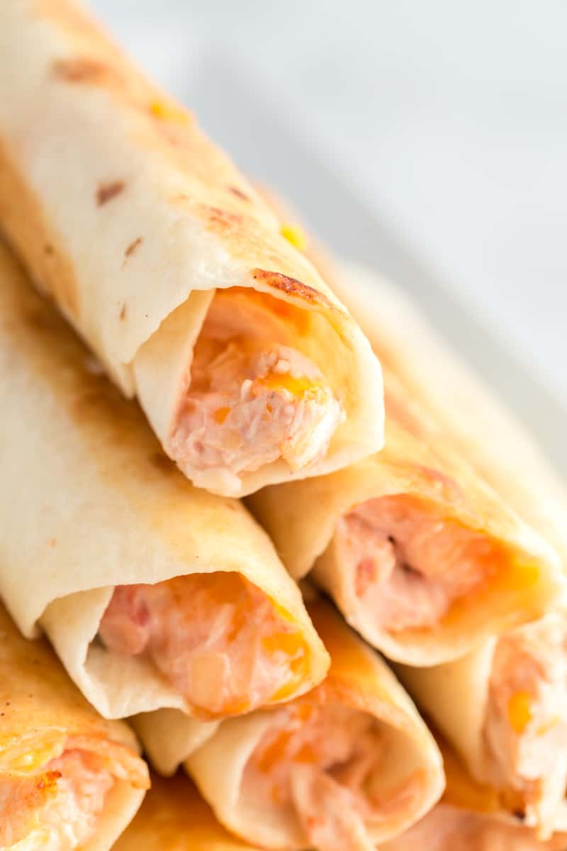 Close up of stacked chicken taquitos showing the cheesy inside