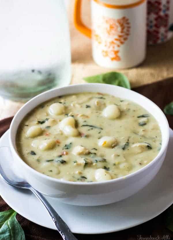 Chicken Gnocchi Soup in bowl with water and salt and pepper shaker in background