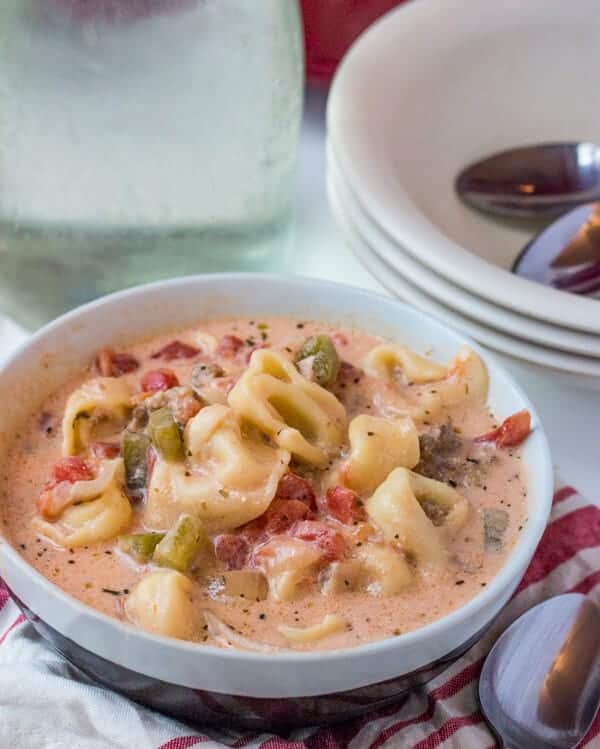 Slow Cooker Tortellini Soup in bowl with bowls in background