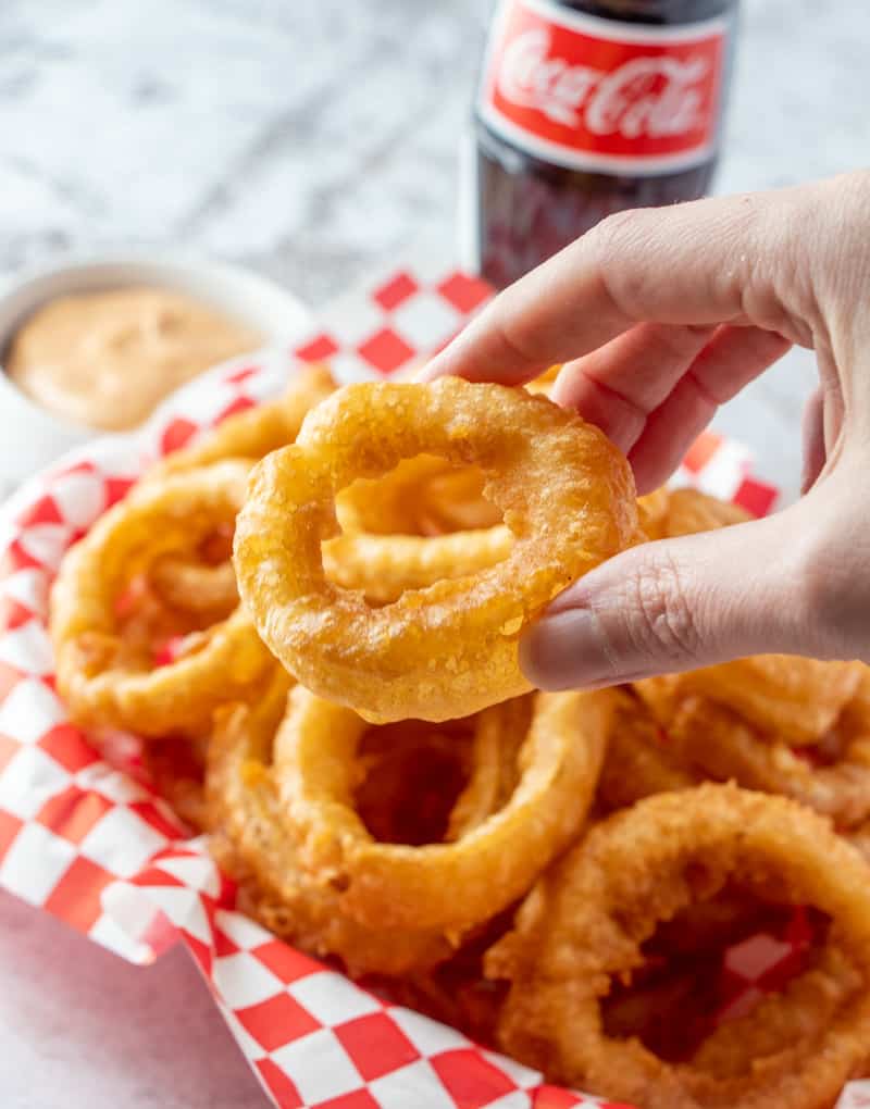 Hand holding onion ring showing the puffy crispy crust