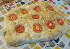 Finished focaccia bread showing tomatoes and herbs on top