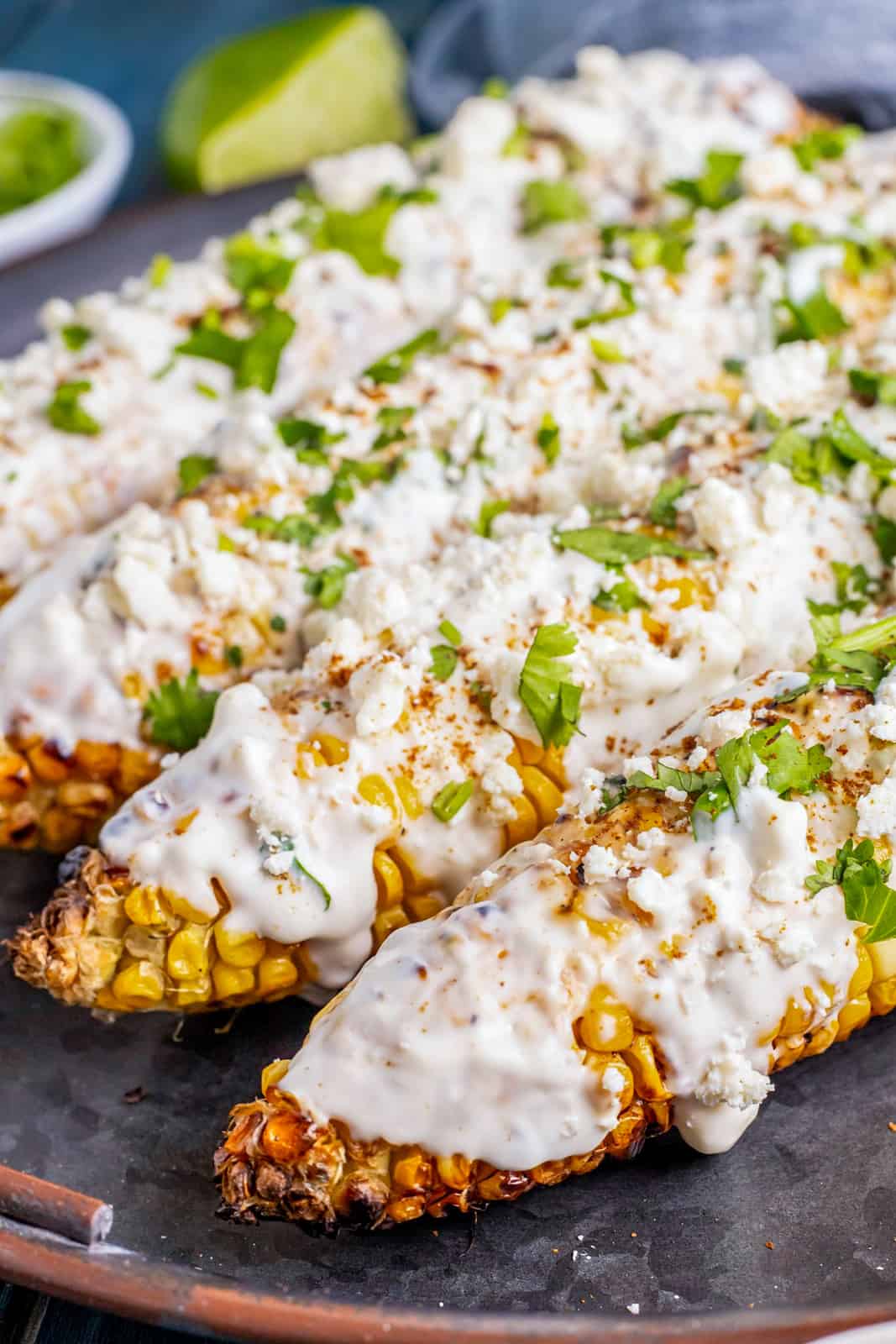 Close up of Mexican Street Corn on black platter showing topping and cilantro