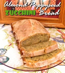 Almond Poppyseed Zucchini Bread glazed with two slices coming off bread loaf on clear plate