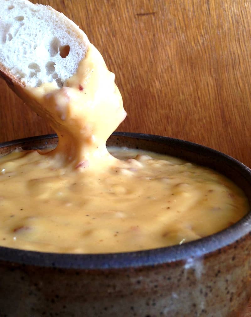 Hand dunking bread into beer dip