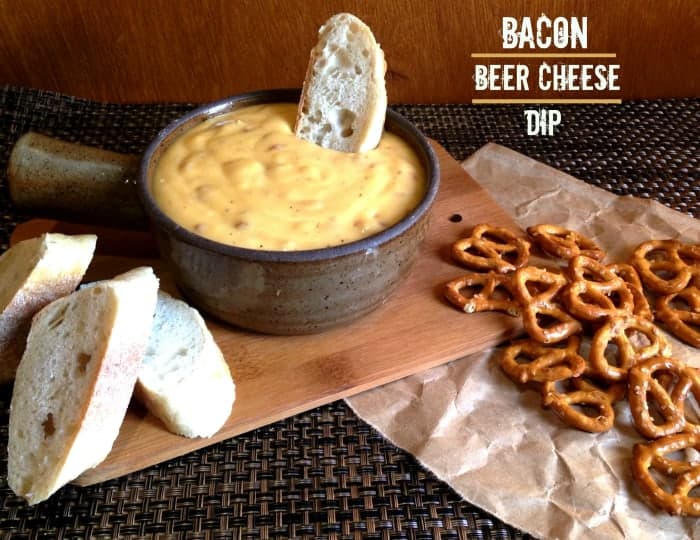 Beer cheese dip in brown bowl with slice of bread in dip surrounded by pretzels