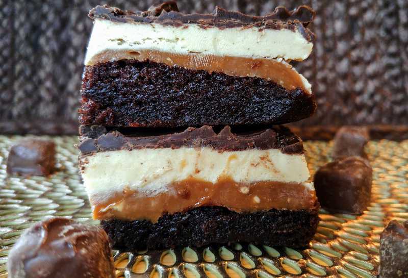 Two brownies stacked on top of one another garnished with mini snickers