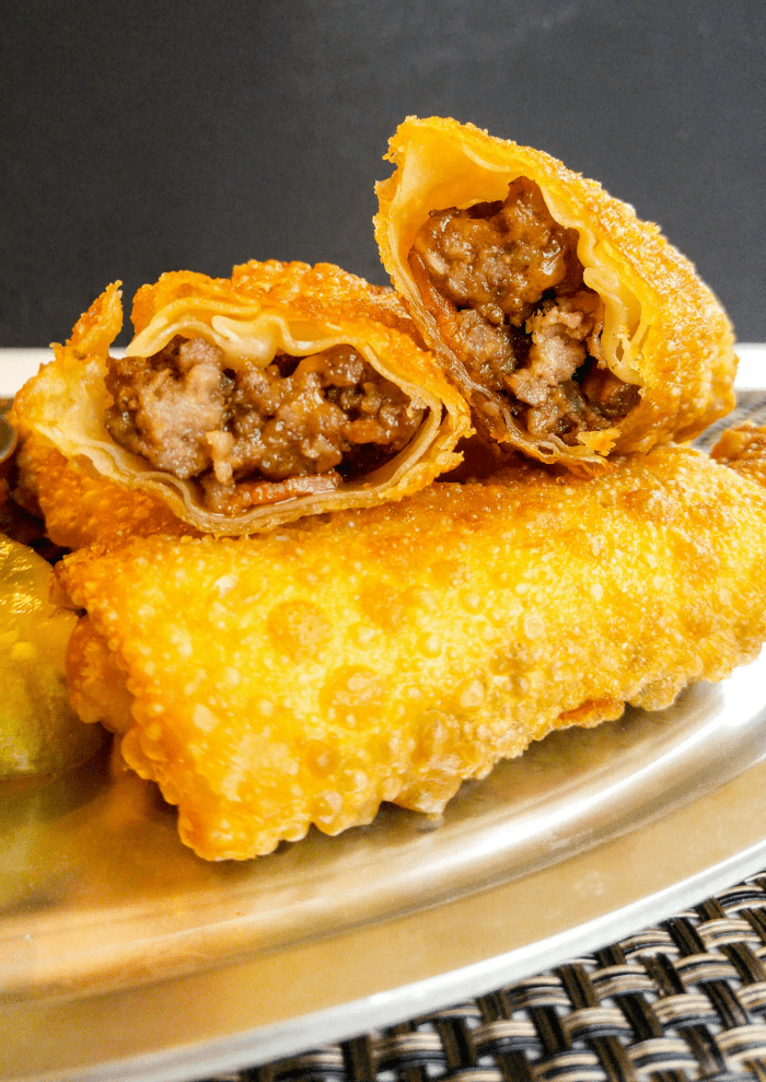 Stacked Bacon Cheeseburger Egg Rolls with one split open so you can see the inside meat