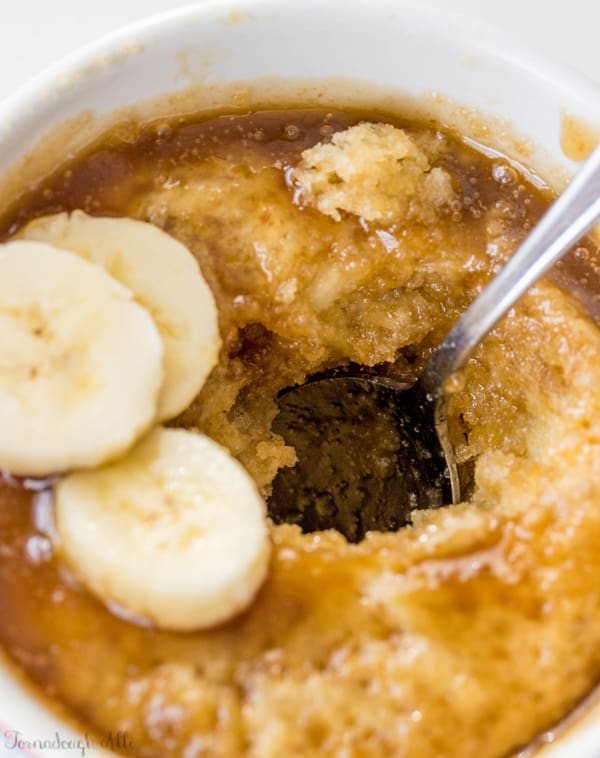 Spoon in banana mug cake showing inside and topped with bananas