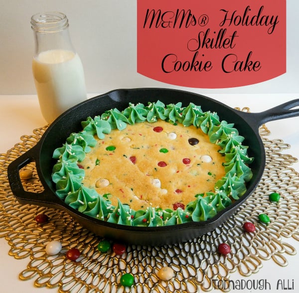 Cookie Cake in cast iron skillet topped with frosting and surrounded by M&M's