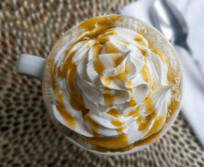 Overhead of hot chocolate in mug topped with whipped cream with caramel drizzle