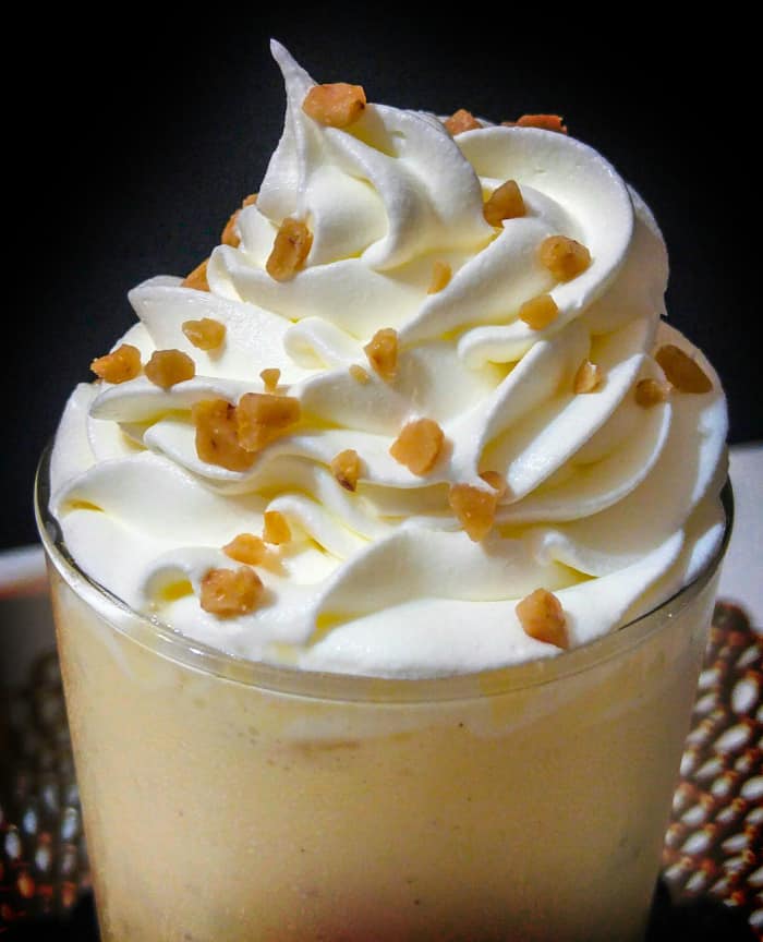 Whipped cream and toffee bits on top of class filled with boozy egg nog shake