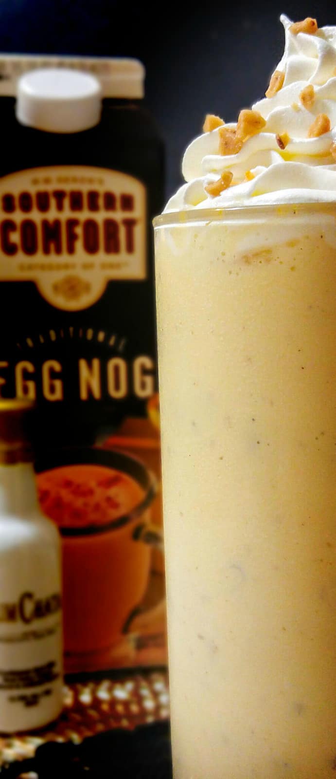 Boozy Egg Nog Shake with bottle of egg nog and rumchata in background