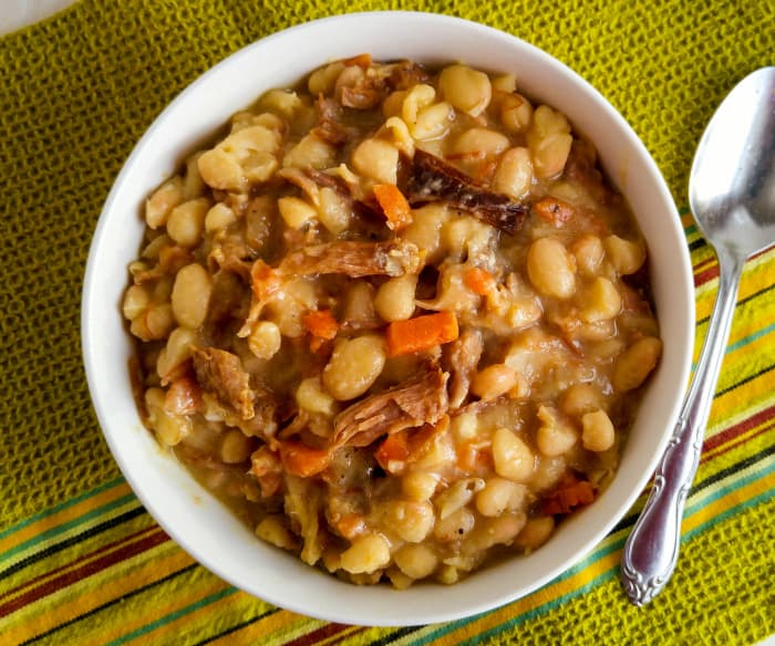 Overhead of Ham and Bean Soup in white bowl with spoon beside bowl