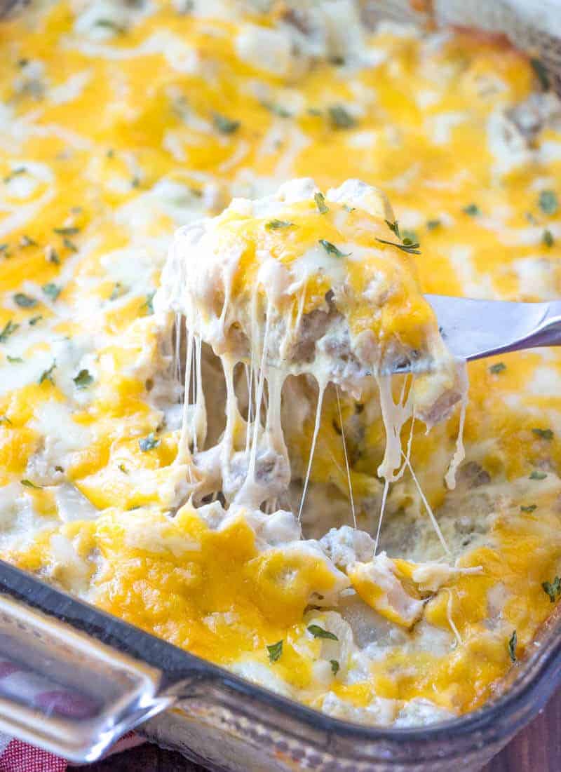 Stuffed Mushroom dip in clear dish with serving knife pulling dip out of dish