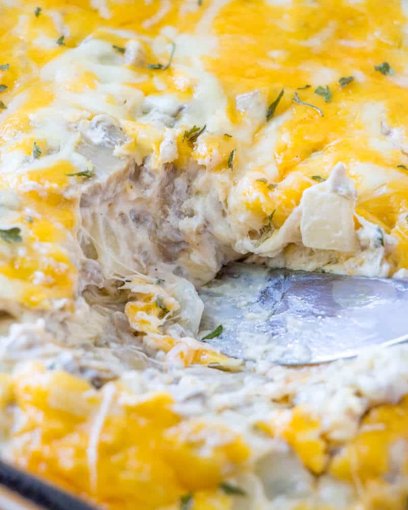 Up close photo of serving knife in dip with cheese and sausage