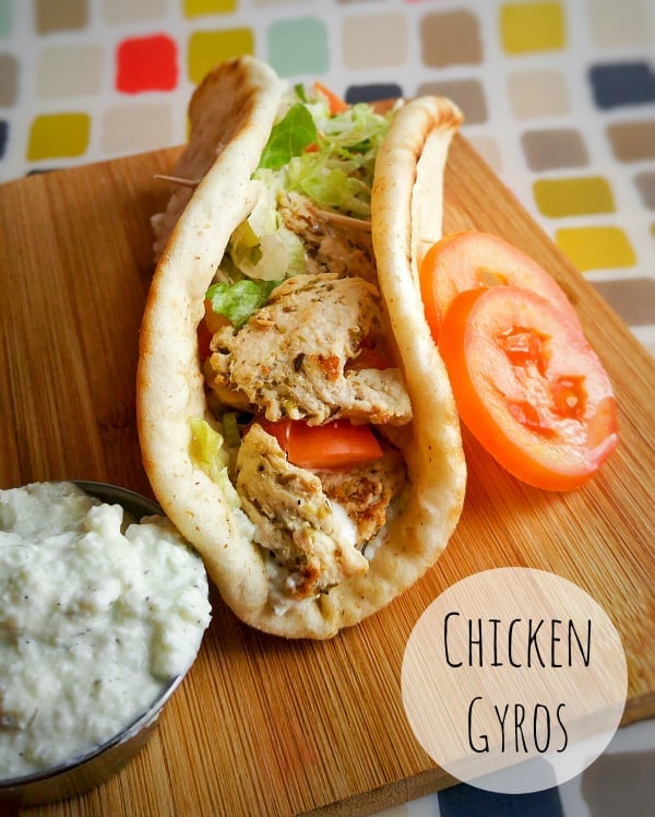 Chicken Gyros topped with lettuce and tomatoes on wooden board