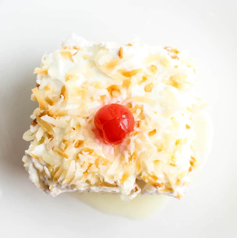 Overhead slice of cake on plate topped with toasted coconut and cherry