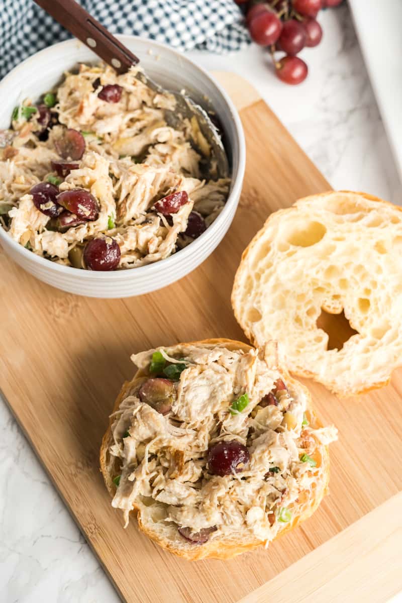 Chicken salad being spread on a cut open croissant