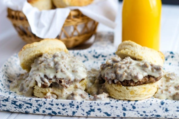 Side View of Two Cheddar Biscuits and gravy on blue and white speckled plate