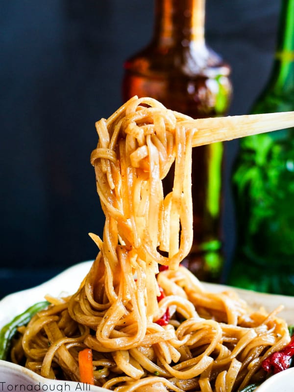 Chopsticks holding up noodles from bowl