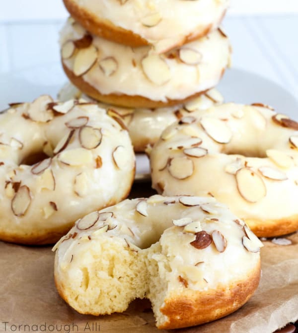 Texas Almond Sheet Cake Donuts on paper bag with one donut with bite taken out