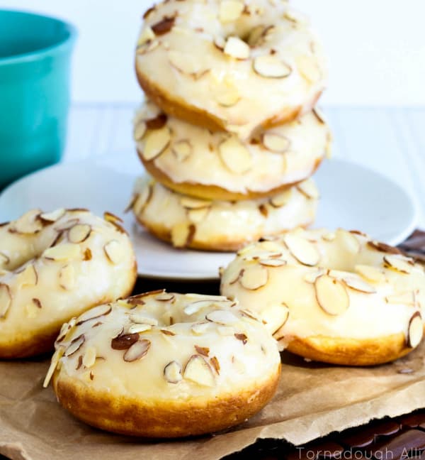 Texas Almond Sheet Cake Donuts stacked in background with three donuts on front