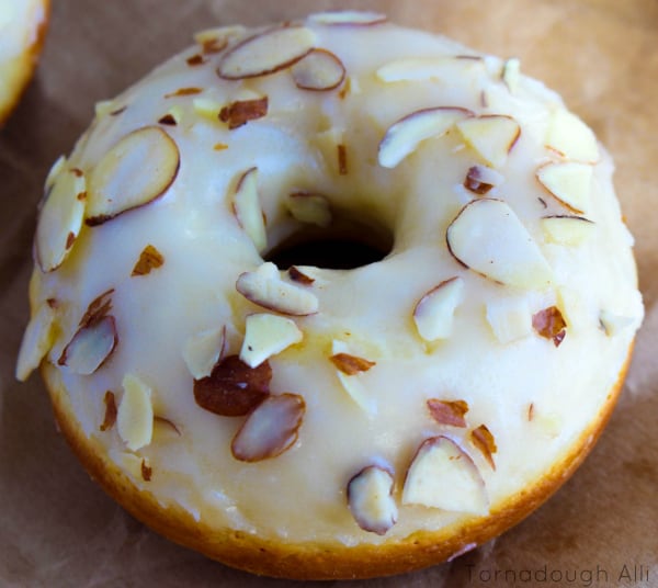 Close up of one donut showing glaze and sliced almonds