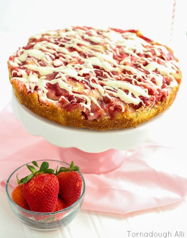 Upside Down Strawberries and-Cream Cake on pink and white cake stand with cream cheese glaze