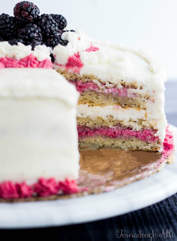 Side view Lemon Poppyseed Cake with Blackberry and Almond Buttercream showing inside with slice cut out