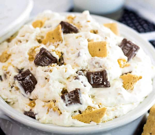 Close up of Cheesecake Fluff topped with broken chocolate bars and graham crackers