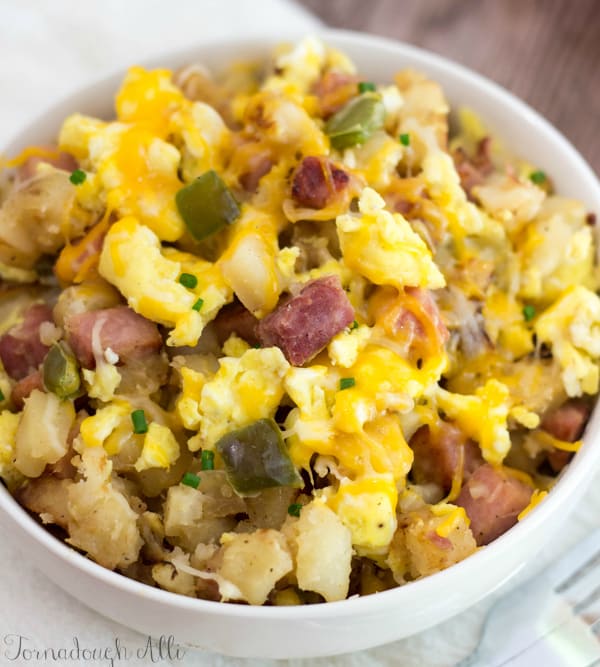 Farmers Breakfast Bowl with potatoes meat ham and eggs in white bowl close up