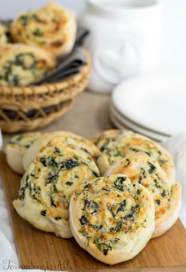 Spinach Dip Pinwheels on cutting board with basket full in background