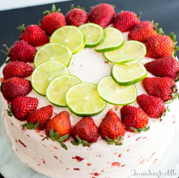 Overhead of finished cake topped with sliced strawberries and limes