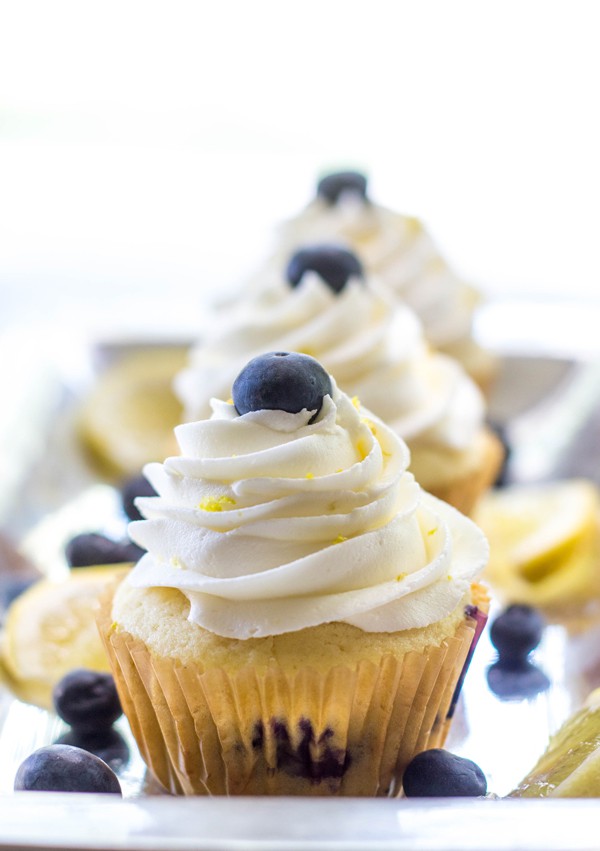 Three Cheesecake Stuffed Lemon Blueberry Cupcakes lined up on metal serving platter