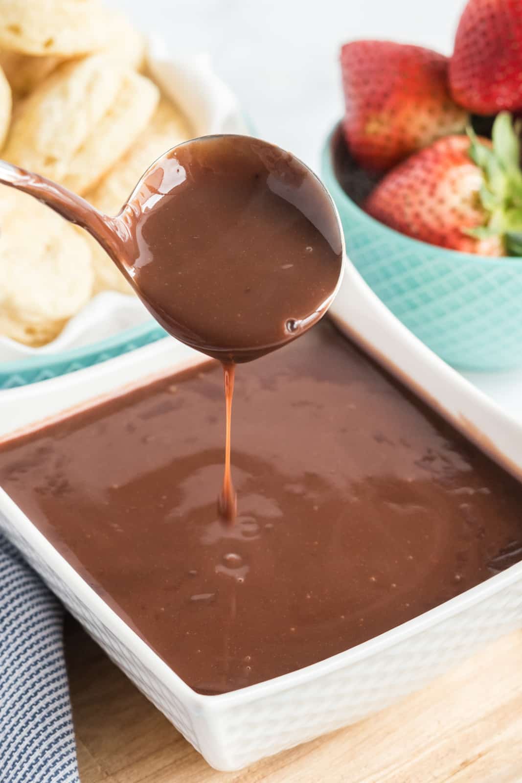 Square bowl of chocolate gravy with ladle spooning out of bowl