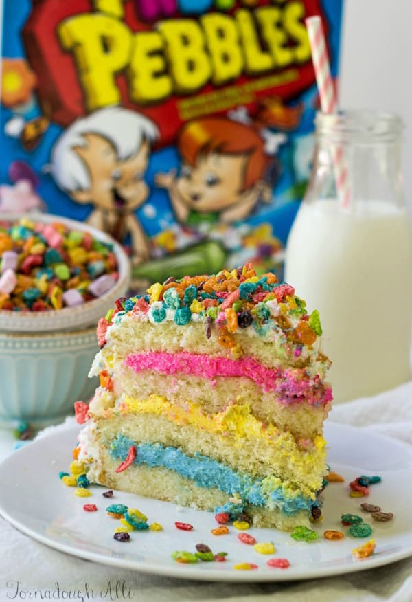 Slice of cake on plate showing blue, yellow and pink frosting layers