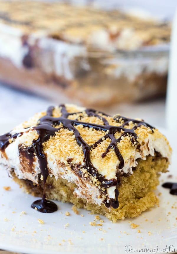 S'mores Poke Cake on plate drizzled with chocolate