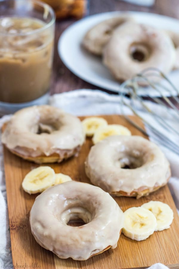 Three donuts on wooden board with banana slices