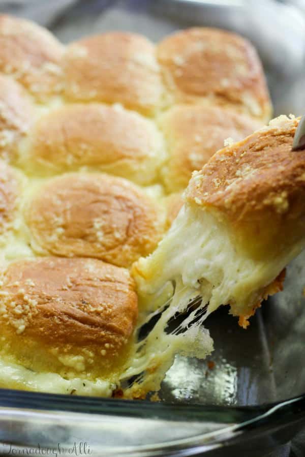 One Cheesy Stuffed Garlic Bread Slider being pulled by hand out of pan
