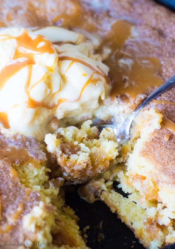 Caramel Apple Stuffed Snickerdoodle Skillet Cookie topped with ice cream and spoon digging into it