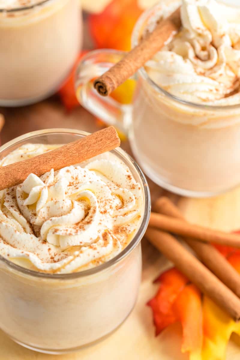 Pumpkin Hot Chocolate in mugs with whipped cream, spices and cinnamon sticks