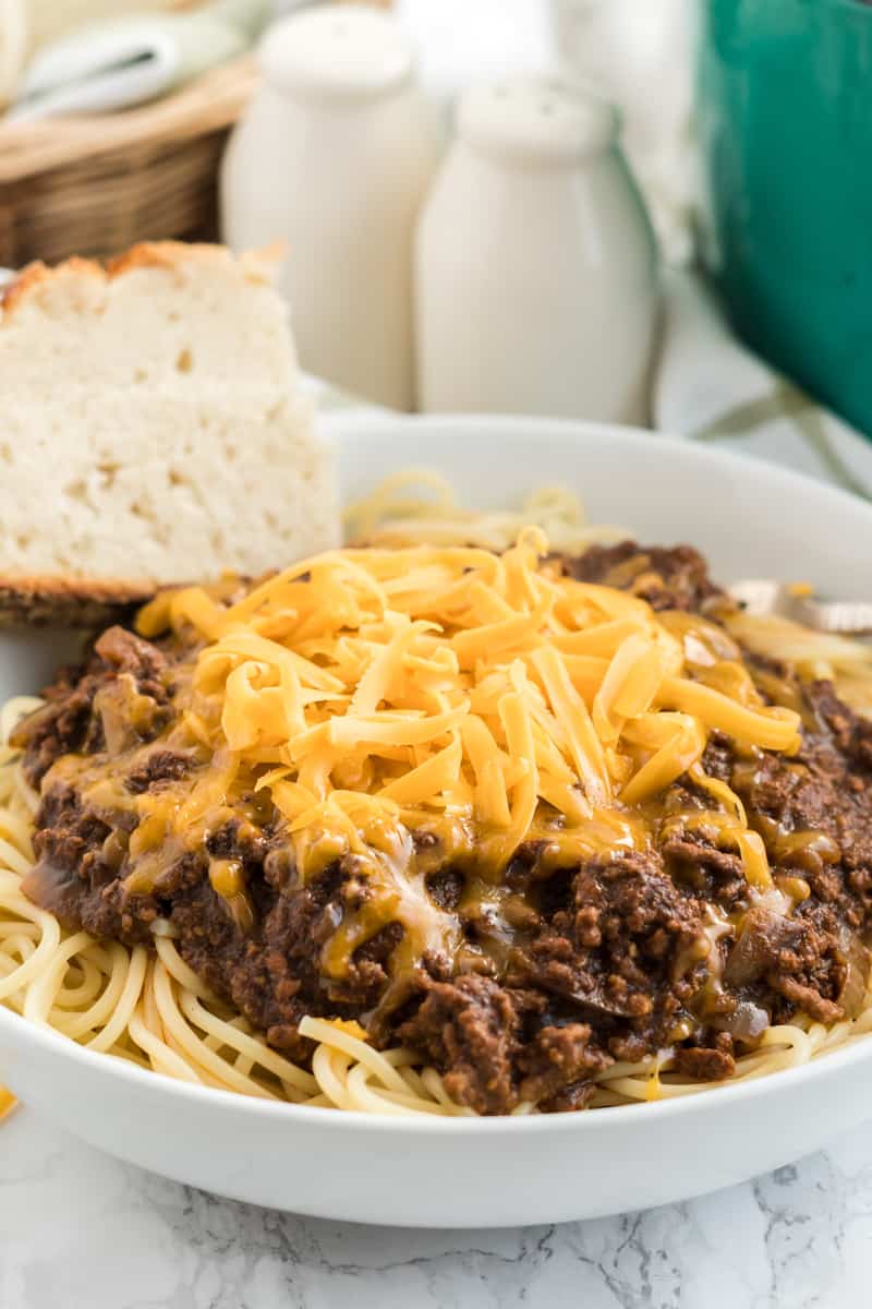 Side photo of Cincinnati chili in bowl with melty cheese over sauce and spaghetti