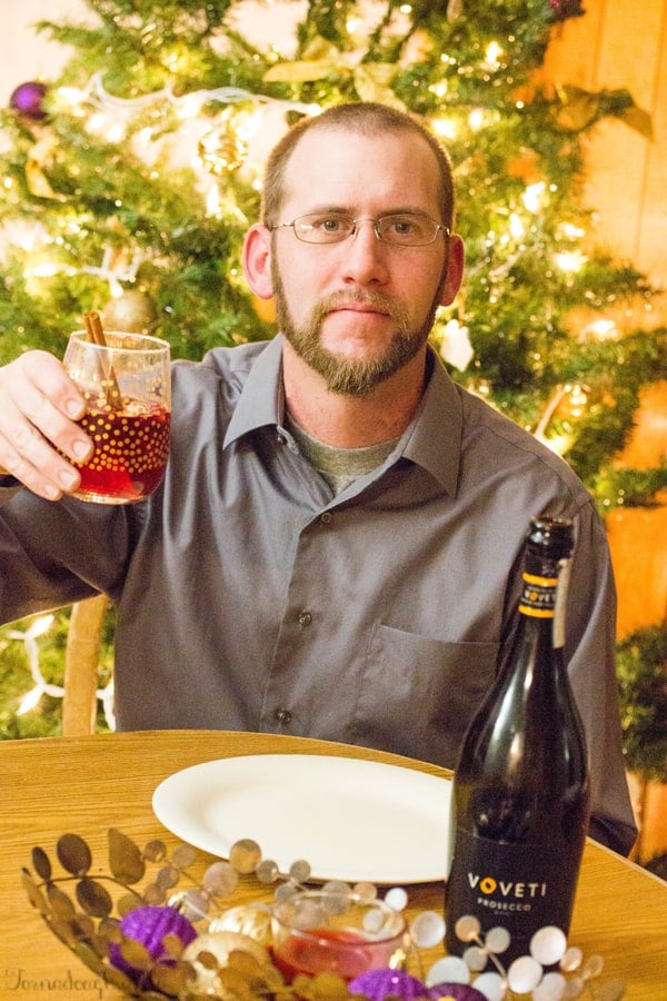 Husband holding up one glass of Cranberry Orange Mimosa