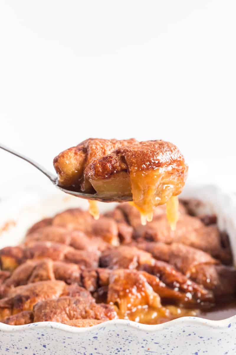 Apple Dumplings on serving spoon out of pan with caramel sauce dripping