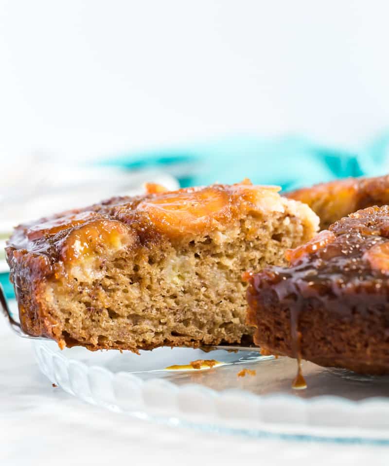 Slice of upside down banana cake being taken from finished cake with caramel dipping down sides