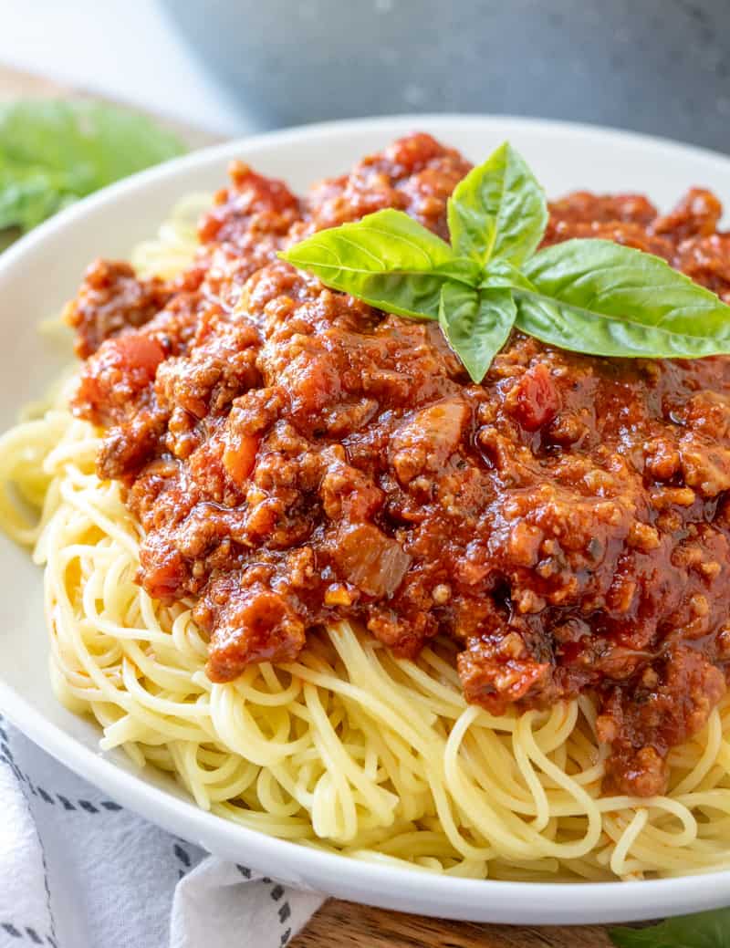 Close up of easy homemade spaghetti sauce served over spaghetti with basil leaves on top