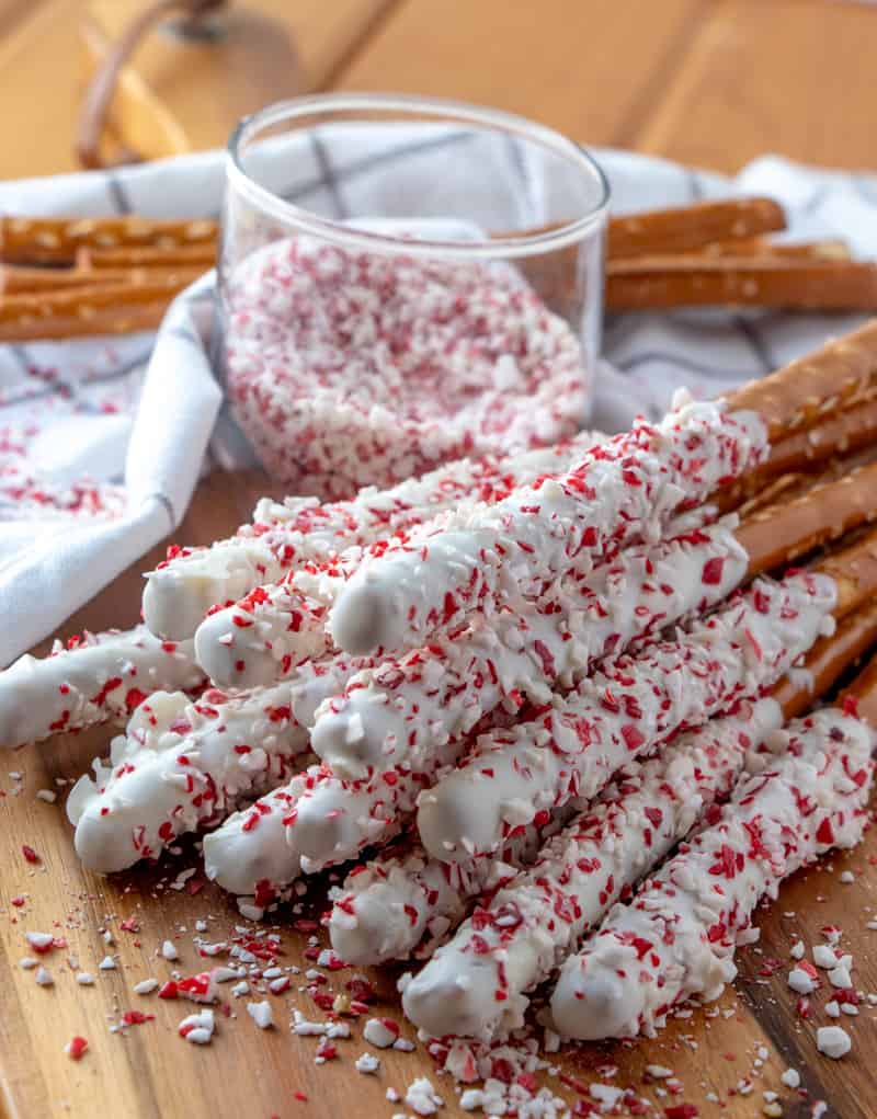 Close up photo of dipped pretzel rods on cutting board covered in crushed candy canes