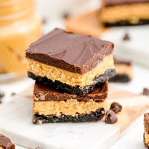 Close up square image of two stacked Peanut Butter Brownies on marble board showing layers.