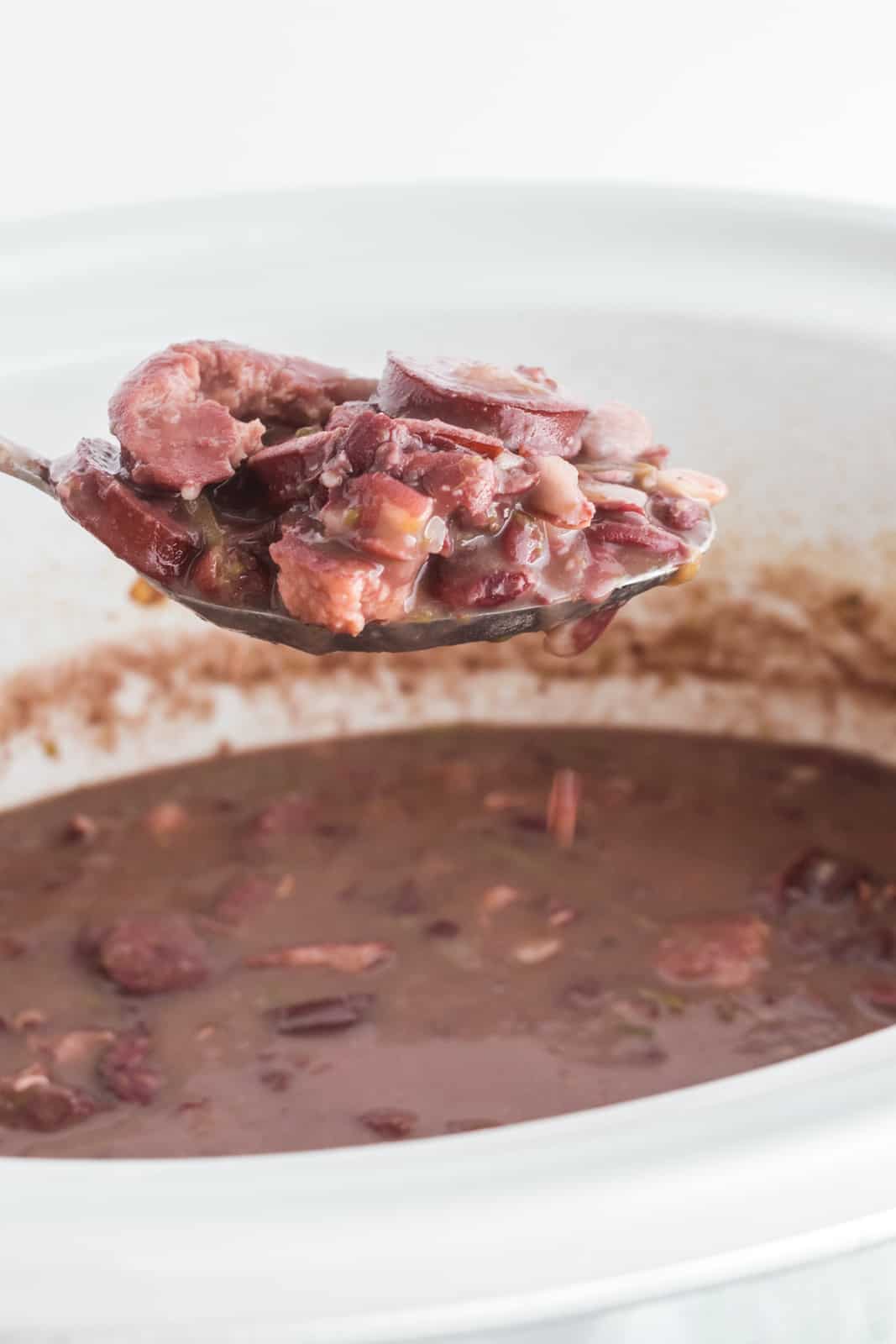 Spoon scooping red beans and rice out of slow cooker