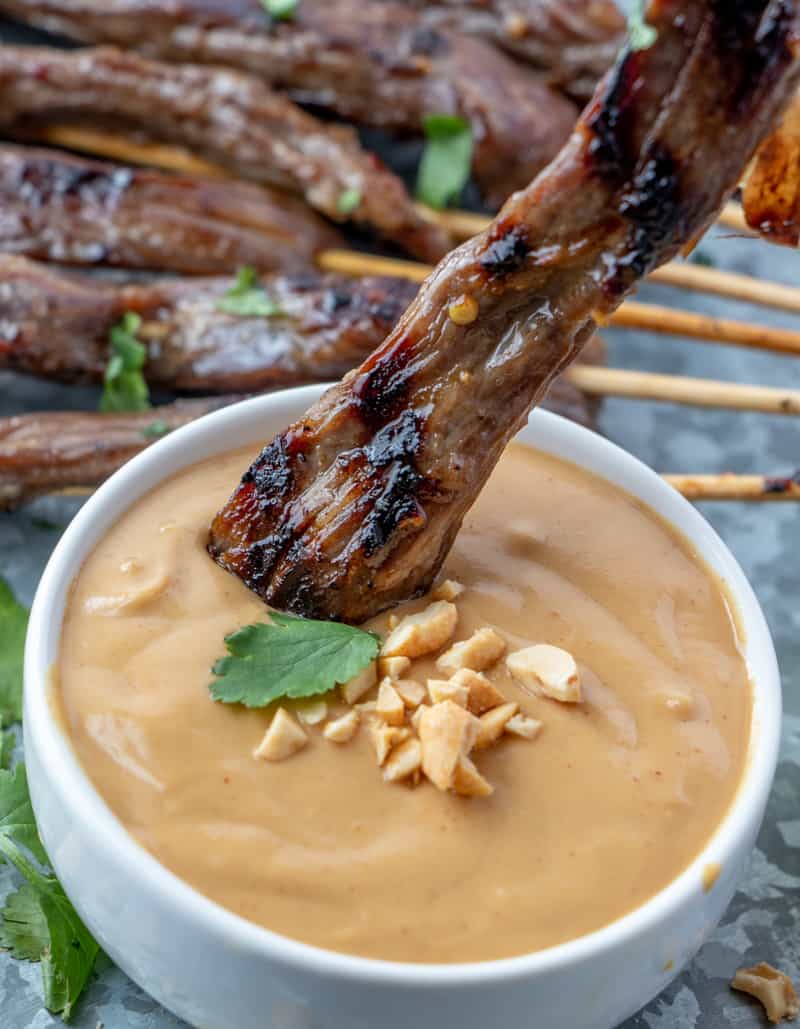 Beef Satay being dipped into peanut sauce